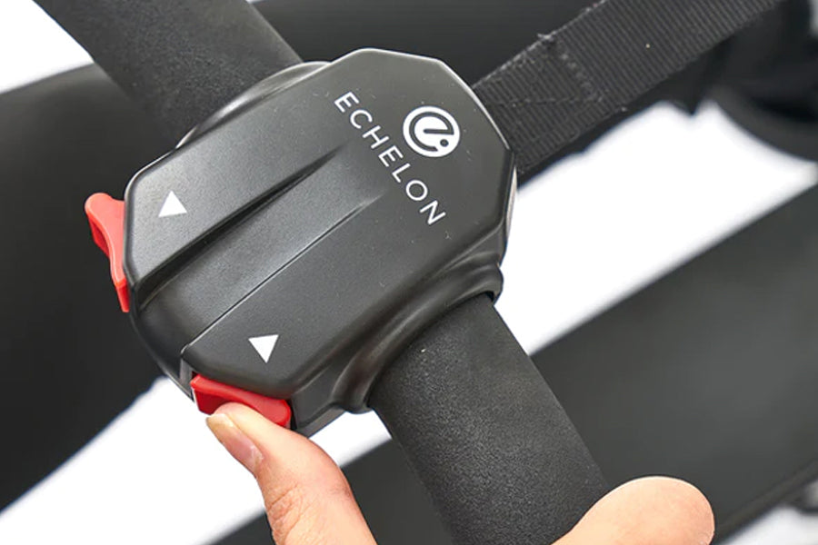 Black Echelon handlebar control unit with red accent buttons held in hand, mounted on rowing machine strap