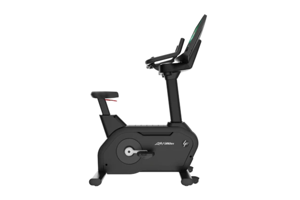 Black upright exercise bike with padded seat, fixed handlebars, and digital display on white background