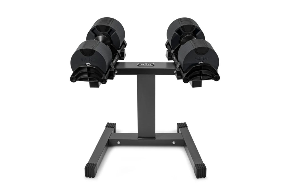 Pair of black adjustable dumbbells on stand with textured grip handles and weight plates, on white background