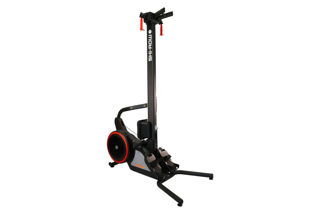 Black and red SKI-ROW Air+PWR rowing machine with tall vertical frame, red-trimmed wheel, and extended footrest on white back